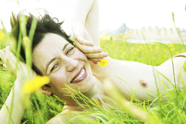 Portrait of smiling nude woman lying in grass - JATF000792