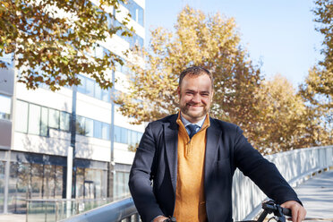 Spain, Barcelona, portrait of smiling businessman with bicycle - VABF000002