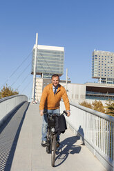 Spain, Barcelona, portrait of businessman riding bicycle - VABF000004