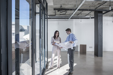 Businesspeople looking at construction plan in new open office - ZEF007550