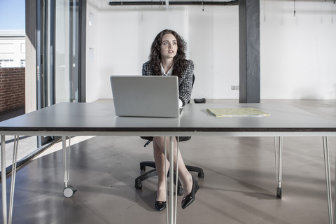 Geschäftsfrau sitzt am Schreibtisch und benutzt einen Laptop, lizenzfreies Stockfoto