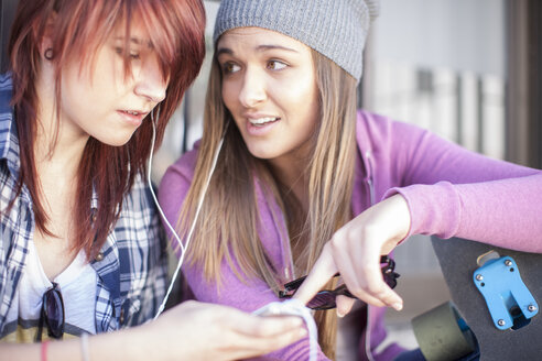 Two friends with skateboard listening to music - ZEF007575