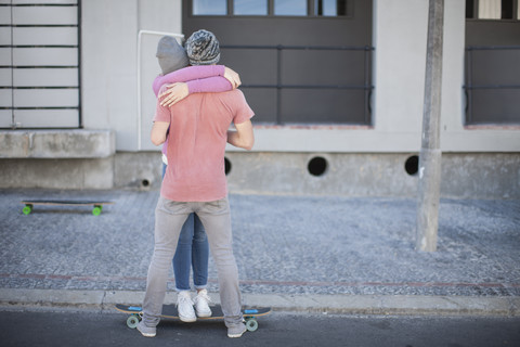 Young couple with skateboard hugging on the street stock photo