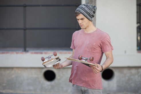 Young man holding broken skateboard - ZEF007618