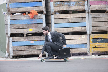 Geschäftsmann fährt auf einem Skateboard - ZEF007622