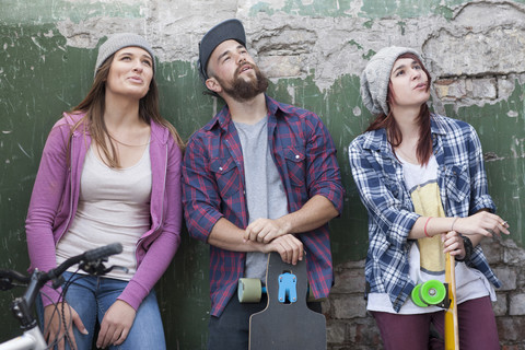 Three stylish friends with skateboards looking up stock photo