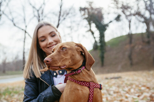 Porträt eines Hundes mit Hundegeschirr mit Besitzer im Hintergrund - ZEDF000025