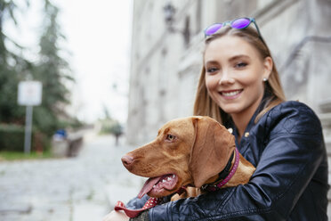 Serbia, Petrovaradin, smiling young woman holding dog in her arms - ZEDF000031