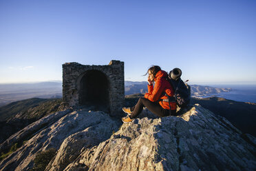 Spain, Catalunya, Girona, female hiker resting on mountaintop looking at view - EBSF001165