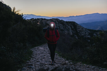 Spain, Catalunya, Girona, female hiker walking with headlamp at twilight - EBSF001174