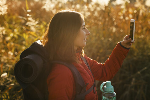 Spain, Catalunya, Girona, smiling female hiker holding cell phone - EBSF001187