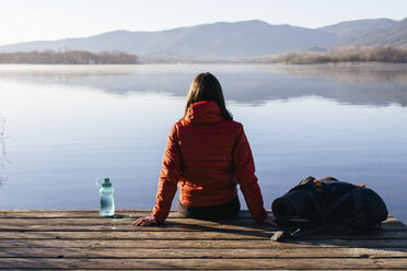 Spain, Catalunya, Girona, female hiker resting on jetty at a lake enjoying the nature - EBSF001190