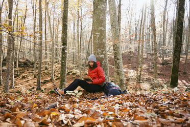 Spain, Catalunya, Girona, female hiker sitting in the woods reading book - EBSF001200