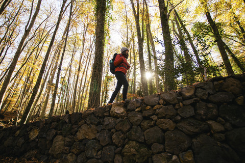 Spanien, Katalonien, Girona, Wanderin geht auf Steinmauer im Wald, lizenzfreies Stockfoto