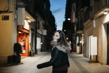 Spanien, Reus, Porträt einer lächelnden jungen Frau in der Fußgängerzone am Abend - JRFF000245