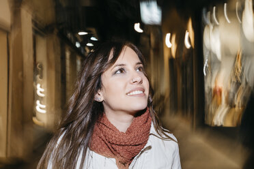 Spain, Reus, portrait of smiling young woman walking through the city at night - JRFF000251