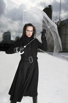 Deutschland, München, Porträt einer schwarz gekleideten Frau auf einem Dach mit durchsichtigem Regenschirm - TMF000091