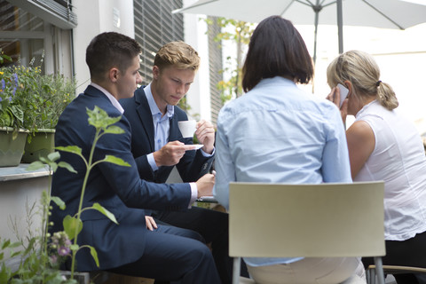 Vier Geschäftsleute sitzen am Tisch im Freien, lizenzfreies Stockfoto