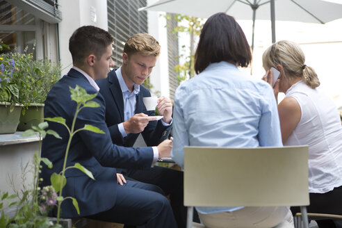 Vier Geschäftsleute sitzen am Tisch im Freien - WESTF021585