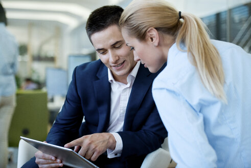 Geschäftsmann und Geschäftsfrau mit Blick auf das digitale Tablet im Büro - WESTF021590