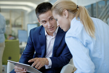 Geschäftsmann und Geschäftsfrau teilen sich ein digitales Tablet im Büro - WESTF021592