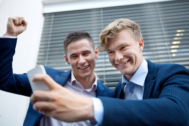 Two happy businessmen looking at cell phone - WESTF021593
