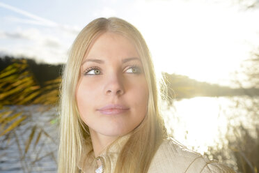 Porträt einer blonden Frau vor einem See bei Gegenlicht - BFRF001706