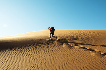 Namibia, Namib Desert, Sossusvlei, Man climbing a dune at sunset - GEMF000549