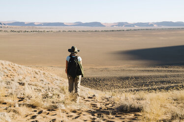 Namibia, Namib-Wüste, Sossusvlei, Frau mit Hut und Rucksack schaut auf den Horizont - GEMF000552