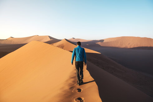 Namibia, Namib Desert, Sossusvlei, Man walking on the top of the famous Dune 45 at sunrise - GEMF000555
