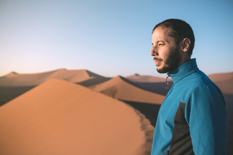 Namibia, Namib-Wüste, Sossusvlei, Mann genießt den Sonnenaufgang von der Spitze der berühmten Düne 45, lizenzfreies Stockfoto