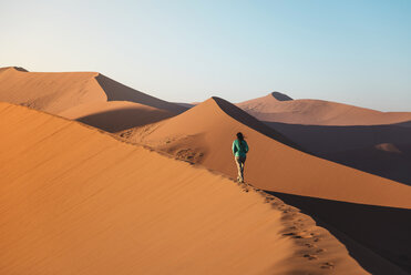 Namibia, Namib Desert, Sossusvlei, Woman walking on Dune 45 at sunrise - GEMF000557