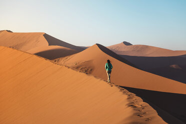Namibia, Namib-Wüste, Sossusvlei, Frau geht bei Sonnenaufgang auf Düne 45 - GEMF000557