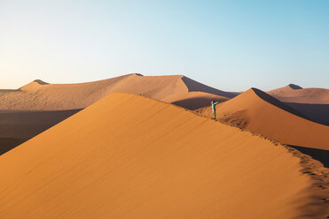 Namibia, Namib-Wüste, Sossusvlei, Frau mit erhobenen Armen auf Düne 45 bei Sonnenaufgang - GEMF000558