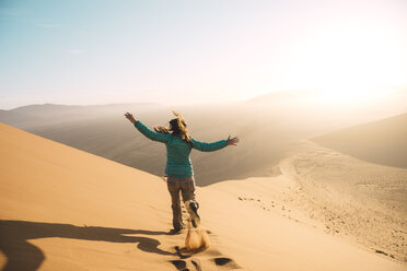 Namibia, Namib-Wüste, Sossusvlei, Frau läuft bei Sonnenaufgang die Düne 45 hinunter - GEMF000559