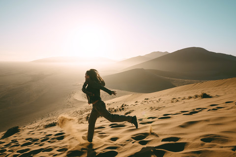 Namibia, Namib Desert, Sossusvlei, Woman running down the Dune 45 at sunrise stock photo