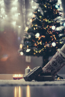 Christmas presents lying on the carpet in front of lighted Christmas tree - JPF000084