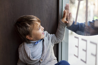 Porträt eines kleinen Jungen, der durch das Fenster auf seinen draußen stehenden Vater blickt - VABF000013