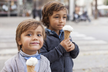 Porträt des glücklichen Kleinen mit Eistüte und seinem Bruder im Hintergrund - VABF000028