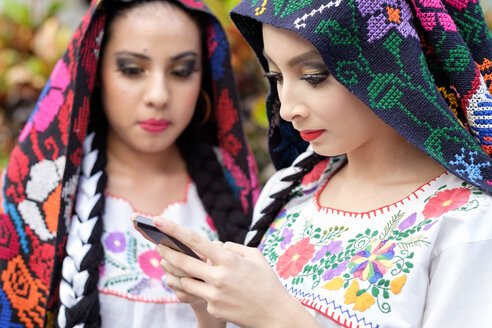 Mexiko, Jalisco, Xiutla-Tänzerin, folkloristische mexikanische Tänzerin mit Smartphone - ABAF001962