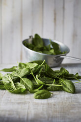 Fresh spinach leaves in colander on wood - KSWF001715