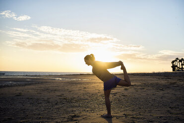 Spanien, Puerto Real, Silhouette einer jungen Frau beim Yoga am Strand bei Sonnenuntergang - KIJF000049