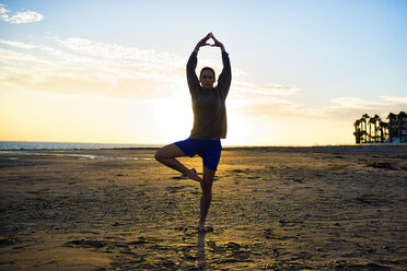 Spanien, Puerto Real, Silhouette einer jungen Frau beim Yoga am Strand bei Sonnenuntergang - KIJF000050