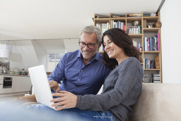 Lächelndes Paar zu Hause auf der Couch mit Laptop - RBF003641