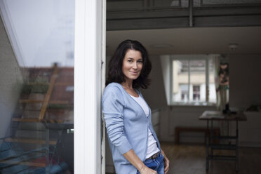 Portrait of smiling woman leaning against balcony door - RBF003666