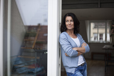 Smiling woman leaning against balcony door - RBF003667