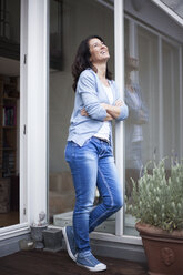 Happy woman standing on balcony - RBF003672