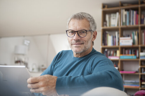 Porträt eines reifen Mannes zu Hause, der ein digitales Tablet hält - RBF003691