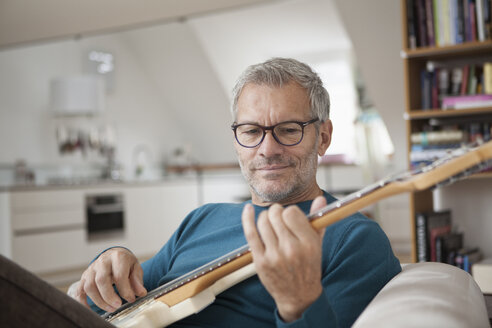 Mature man at home playing guitar - RBF003695