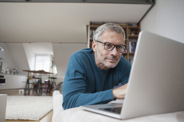 Älterer Mann zu Hause auf der Couch liegend mit Laptop - RBF003701